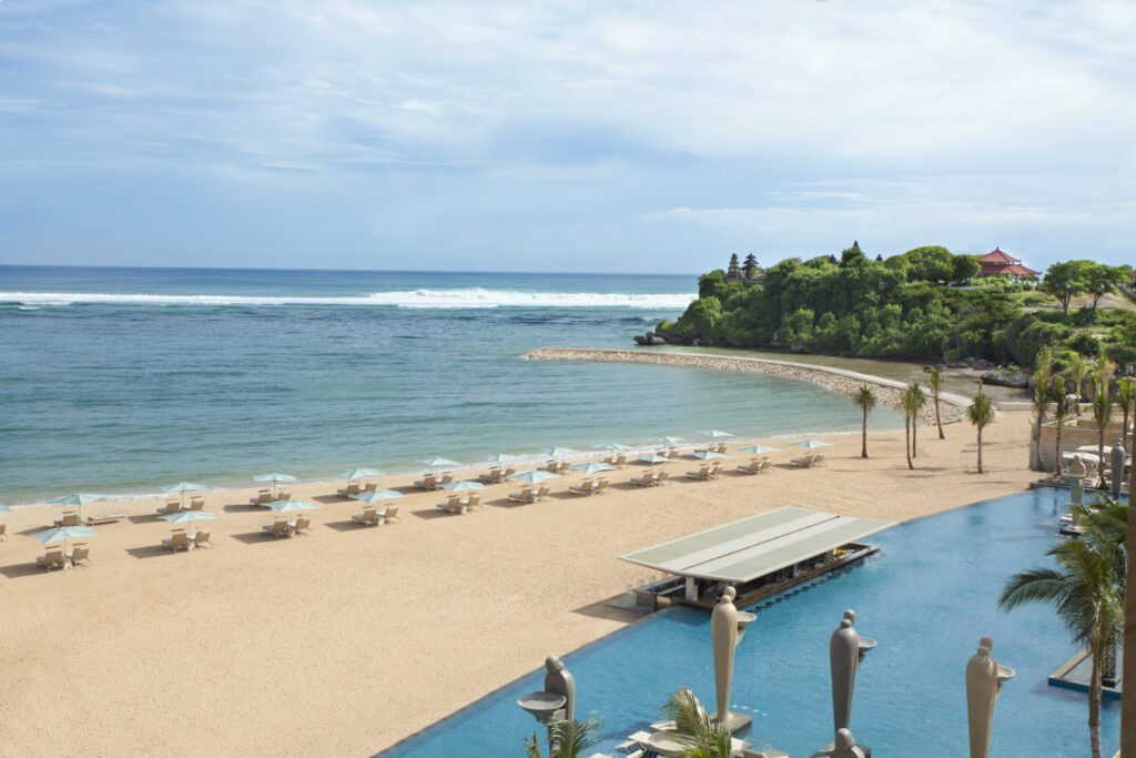 A  view of the private beach from the Mulia Bali Resort, overlooking the turquoise ocean, neighboring cliff and the Ocean Pool - Luxury Escapes