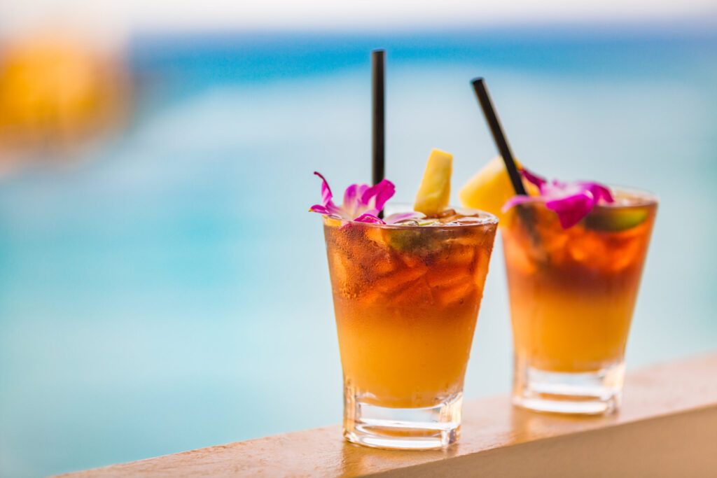 Two delicious Hawaiian Mai Tais, each with a dark rum float, on Waikiki Beach - Luxury Escapes