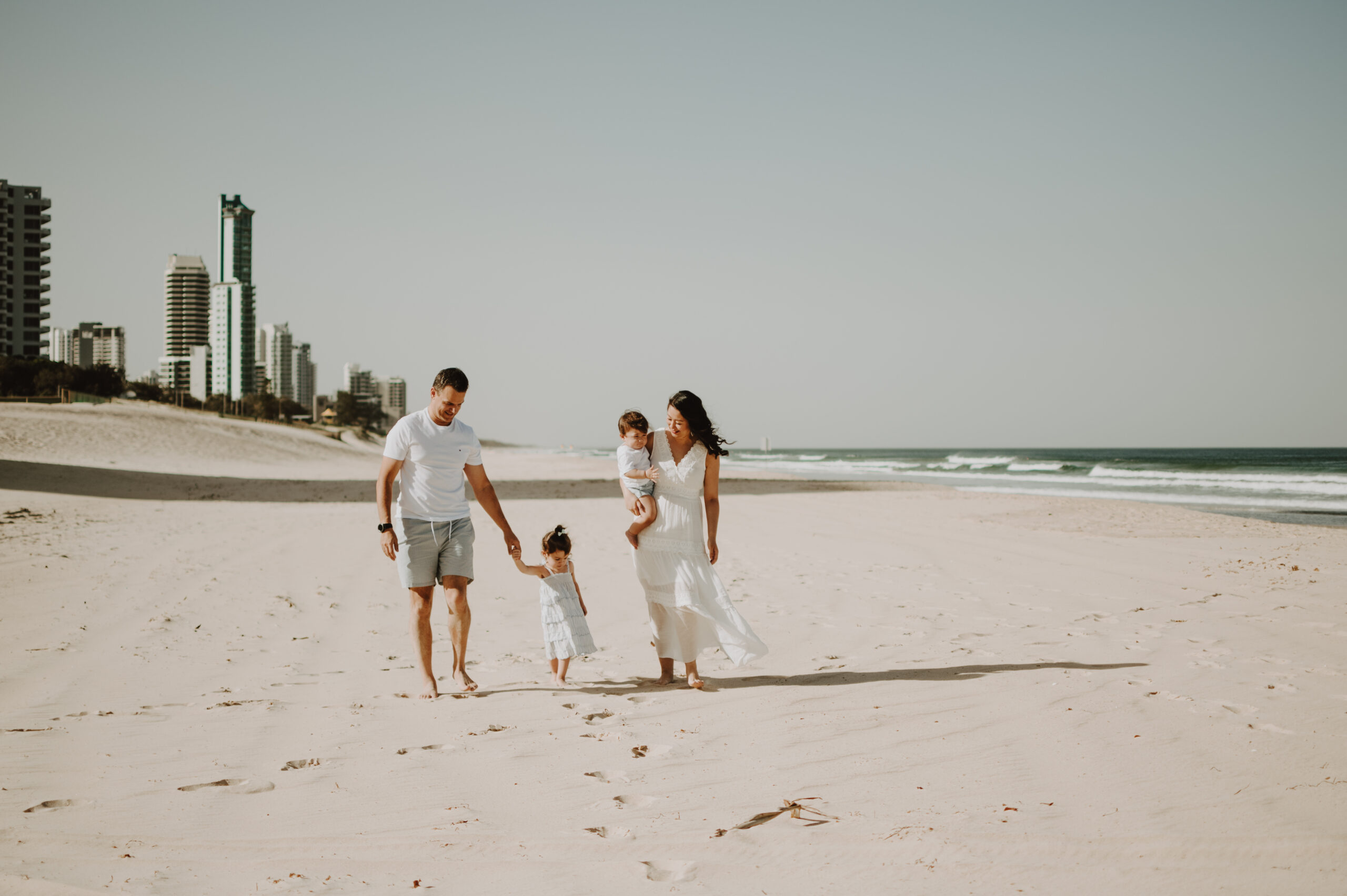 A family walks on Surfers Paradise Beach in the Gold Coast on a sunny day.|||