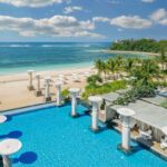 View of the Oasis pool looking out over the beach and ocean at The Mulia, to illustrate an article about The Mulia Bali - Luxury Escapes