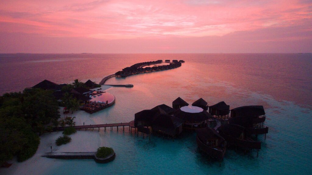 Sunset aerial view of Lily Beach Resort & Spa's over water villas. - Luxury Escapes