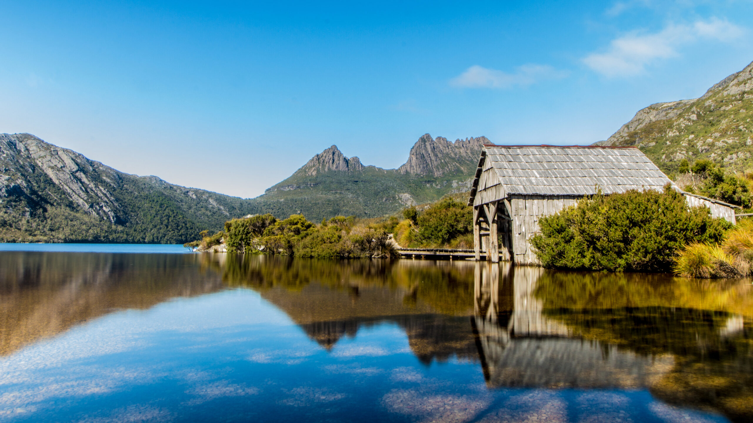 View of a hut on the edge of a lake in Cradle Mountain, one of Tasmania's most romantic getaway locations - Luxury Escapes