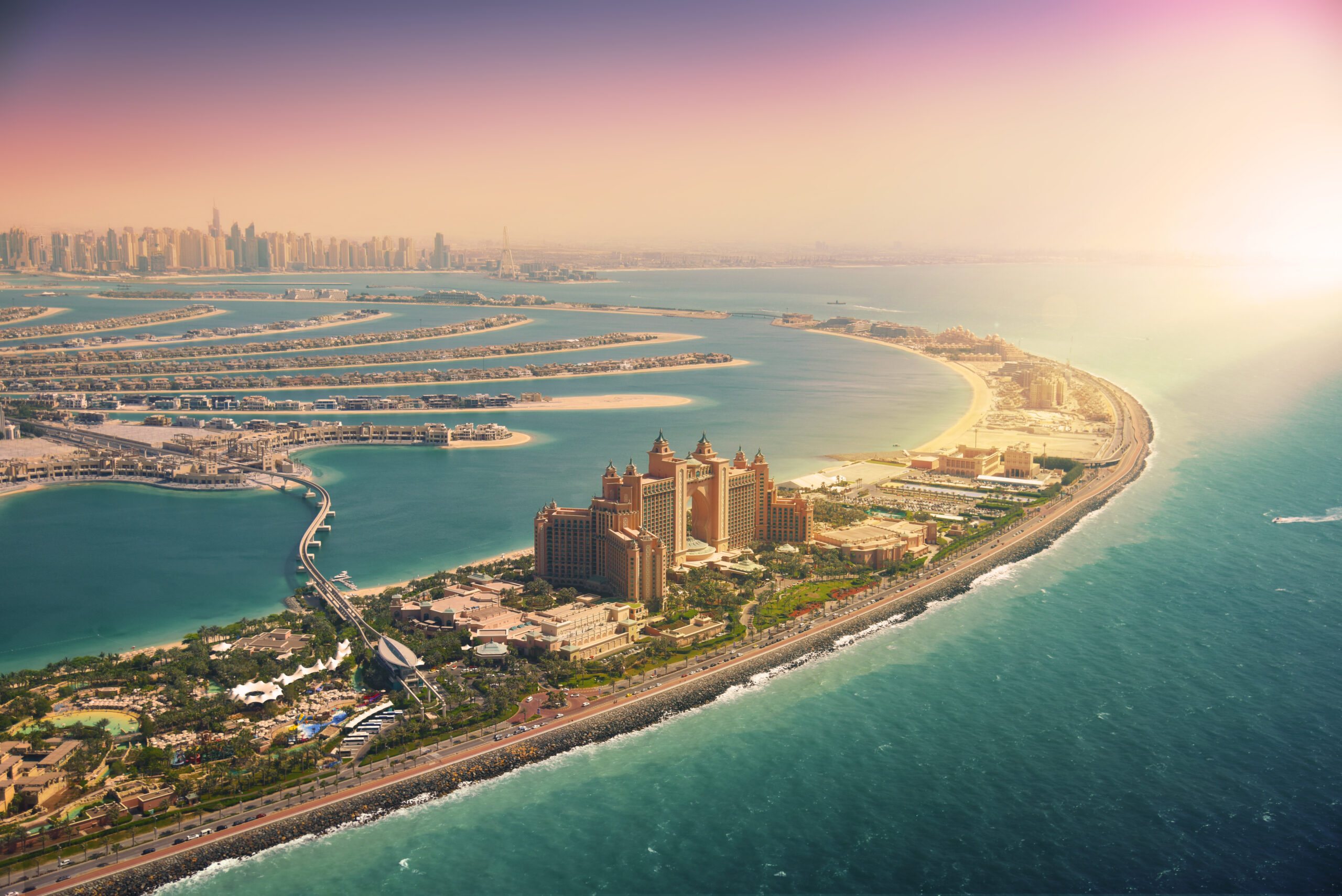 Palm Jumeirah from above with colourful sun set in the distance on the horizon|||