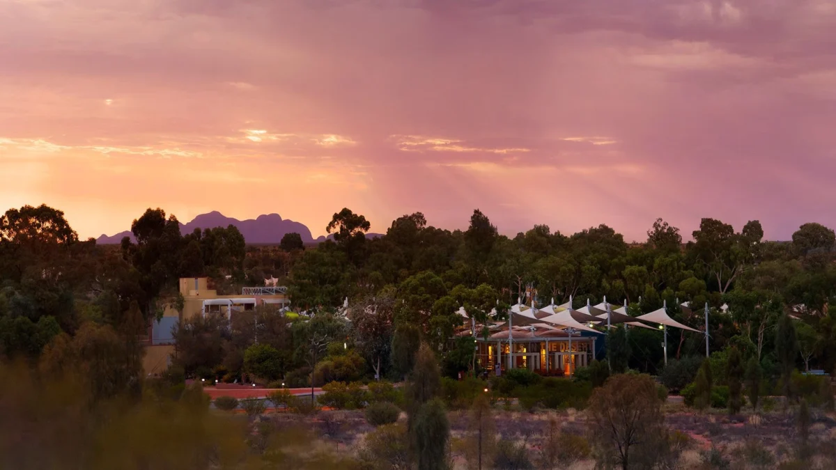 An evening shot of bucket-list worthy hotel Sails in the Desert, with Uluru's striking form visible in the background