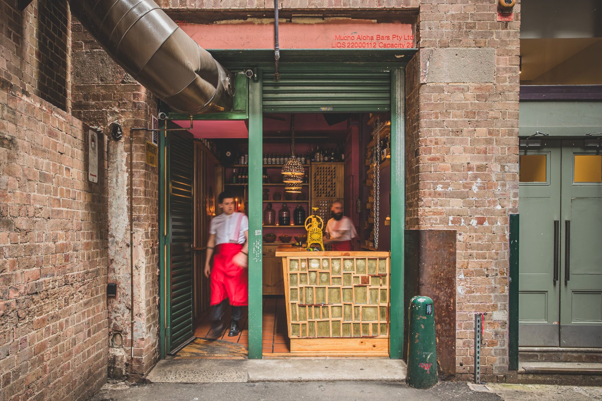 Two bartenders with red aprons wait for customers to arrive to Cantina OK!, one of Sydney's top 10 bars of 2023 - Luxury Escapes