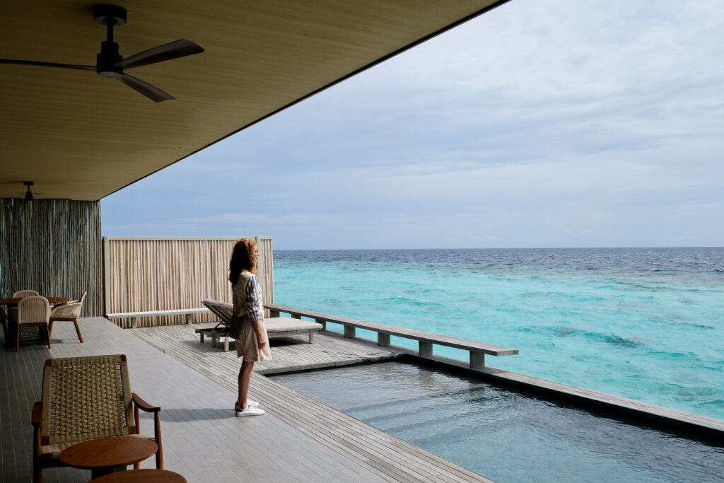 Heather Mitchell stands in front of a beautiful pool in her villa in the Maldives - Luxury Escapes 