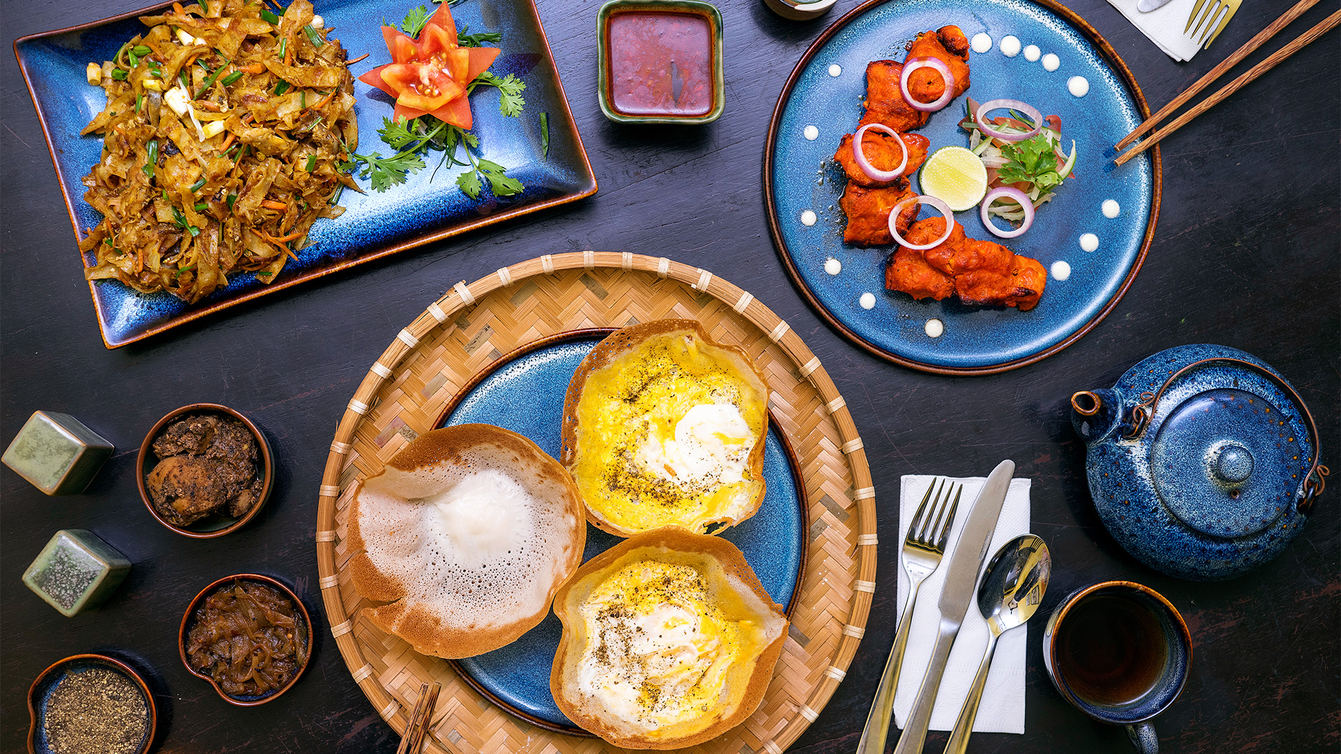 An array of delicious plates with rice, chicken and seafood on a table at A Minute by Tuk-Tuk, Galle, one of Sri Lanka's top 6 best restaurants with must try dishes - Luxury Escapes