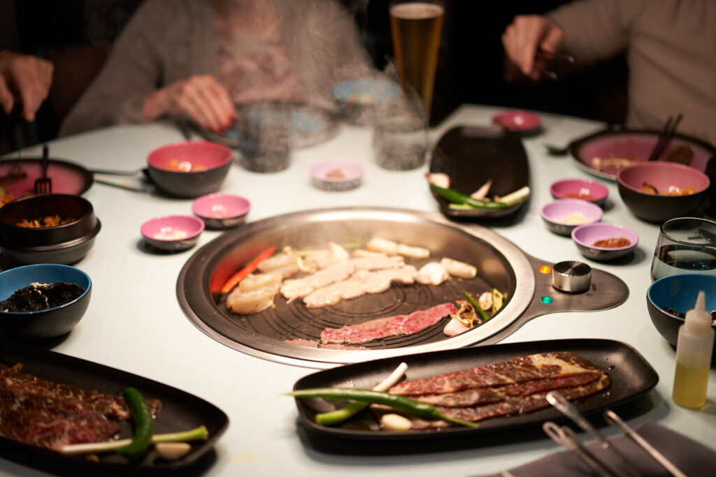 A meal on the table grill at Gunbae Korean BBQ aboard the Resilient Lady, a Virgin Voyages cruise - Luxury Escapes
