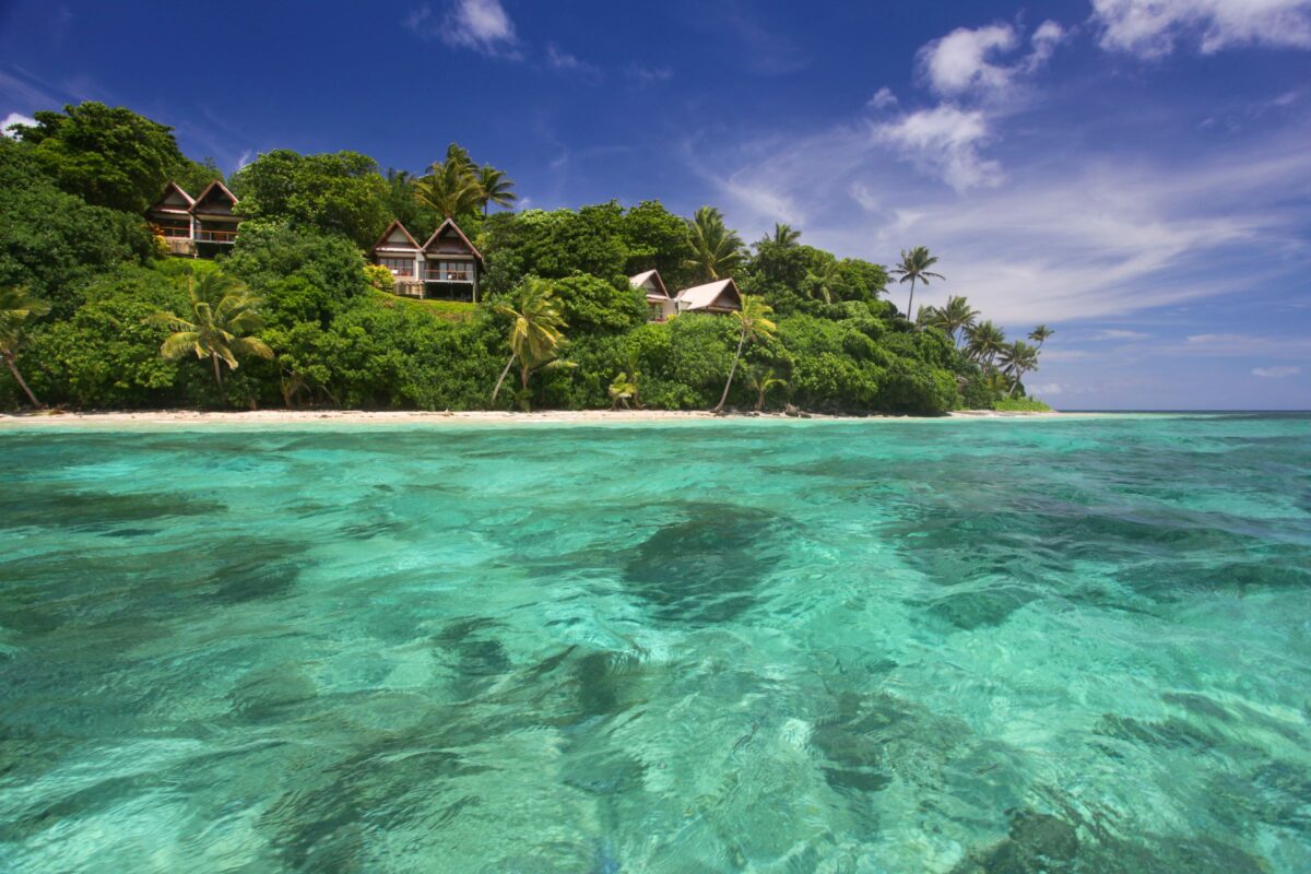 A classic shot of Fiji with the clear sky and emerald green waters - Luxury Escapes