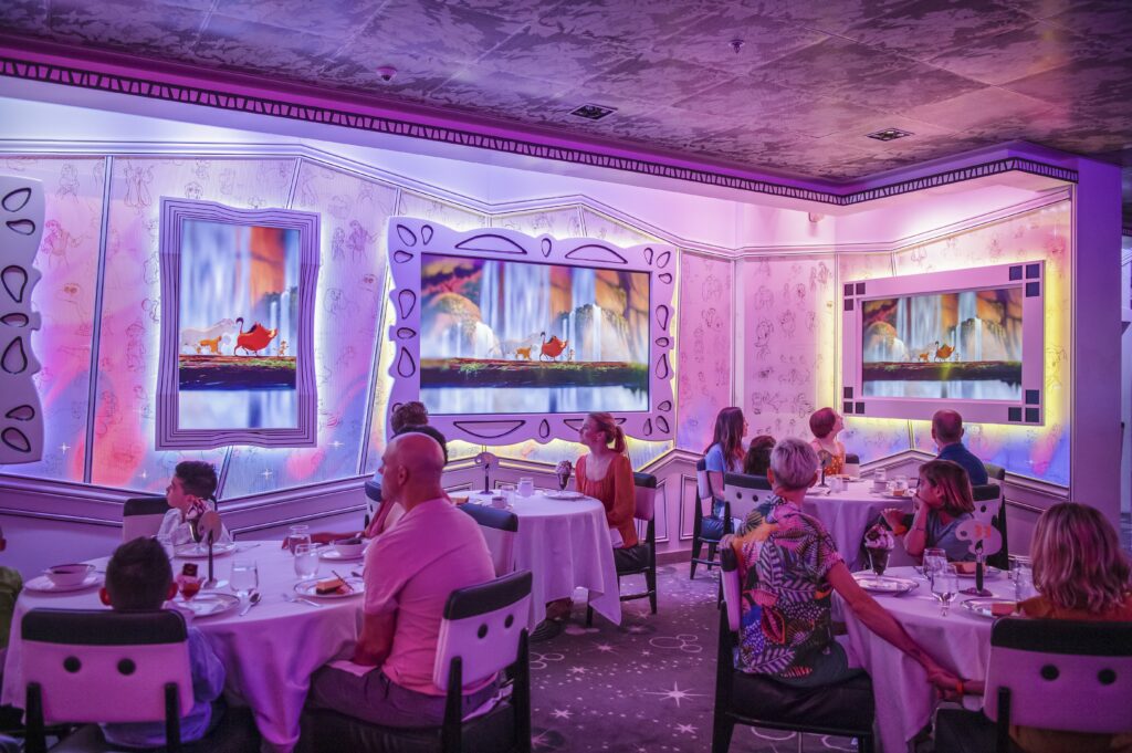 Diners sitting down to eat a meal inside Animators Palate restaurant, one of many restaurants aboard the Disney Cruise Line - Luxury Escapes