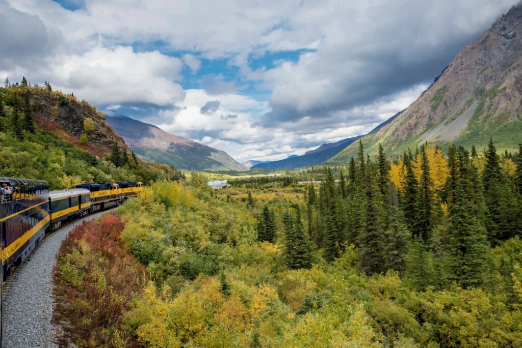 The Autumn landscape of Alaska with lush greenery everywhere and the railroad - Luxury Escapes