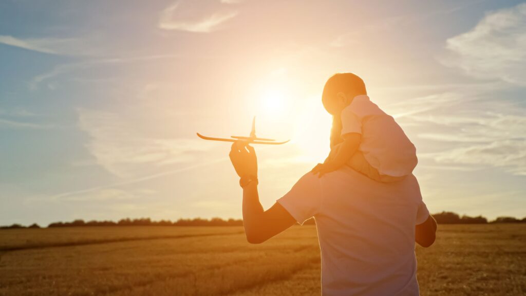 Father flying a toy airplane with his child, preparing for a flight with a toddler.