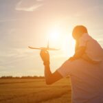 Father flying a toy airplane with his child, preparing for a flight with a toddler.