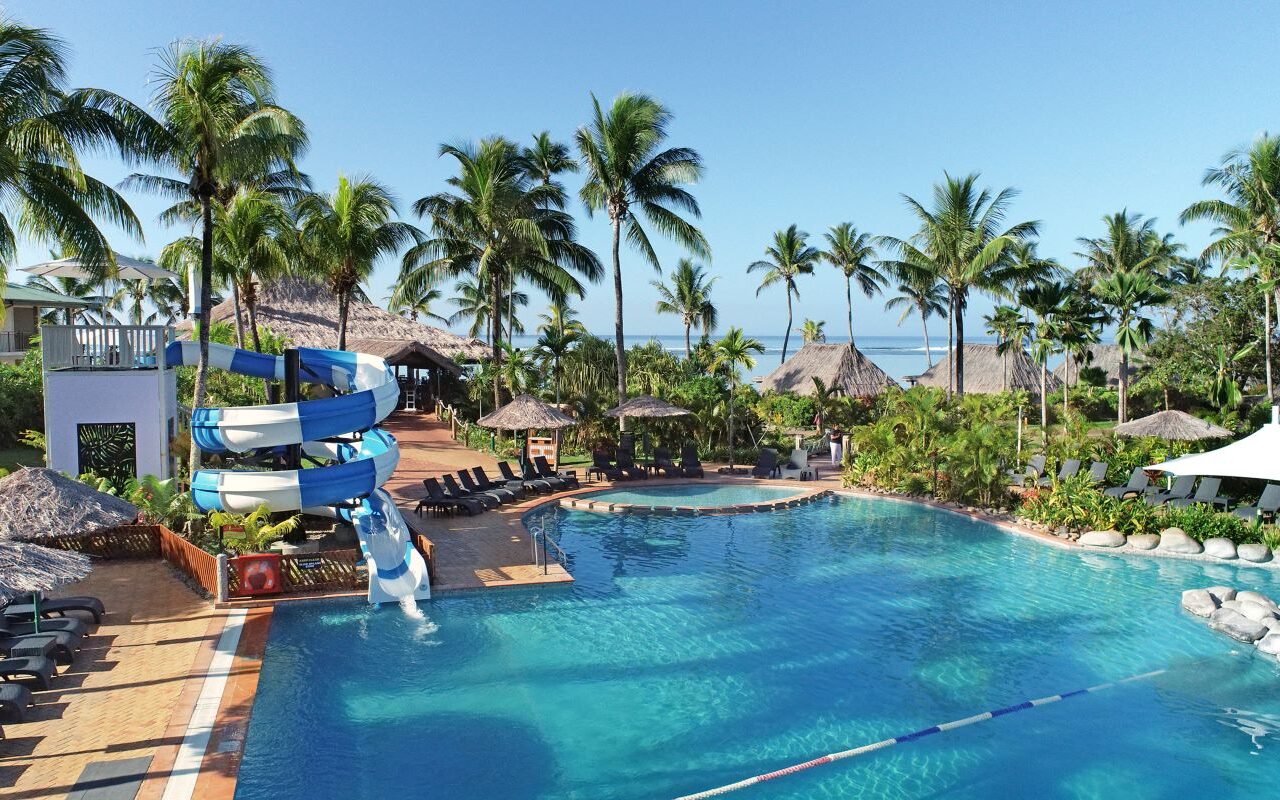 An water slide flows into the sparkling lagoon pool, perfect for kids, at Outrigger Fiji Beach Resort, one of the best places to stay in Fiji on a weekend away from Brisbane - Luxury Escapes