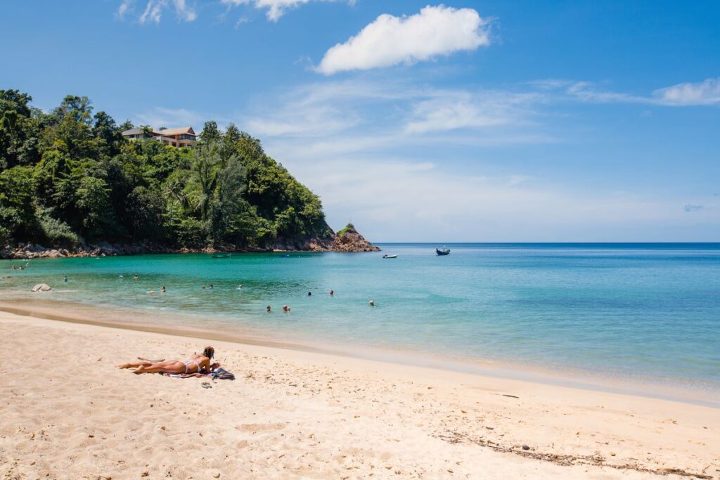 A beachgoer laying on a towel in the sun on Banana Beach, the favourite beach of Phuket's locals