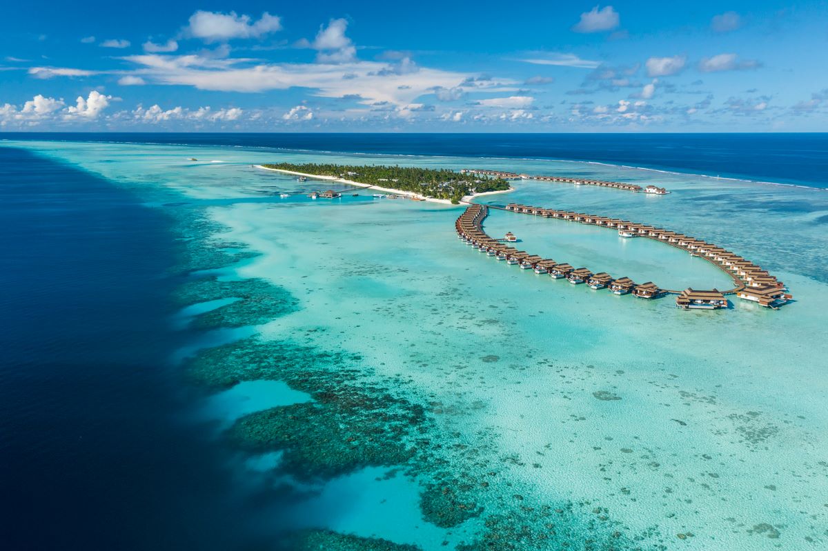 An aerial view of the Pullman Maldives Maamutaa resort and surrounding blue waters which is one of the best overwater all-inclusive resorts in the Maldives - Luxury Escapes