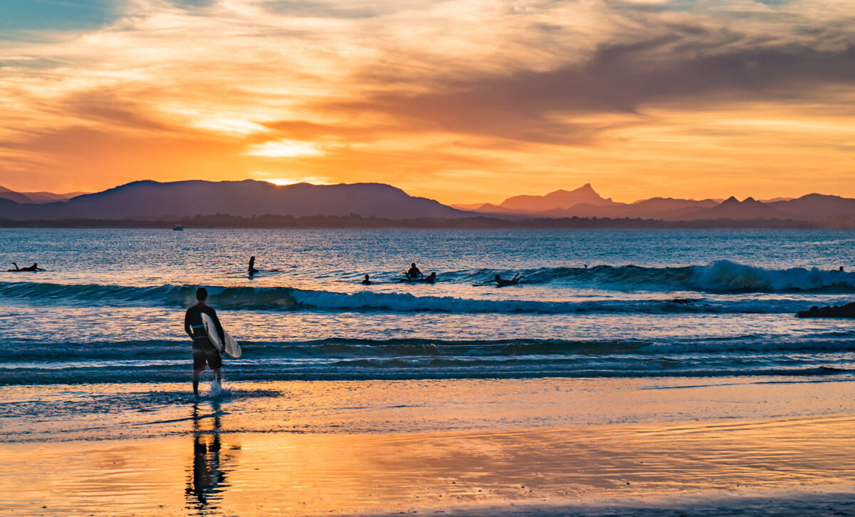Sunset at The Pass in Byron Bay with a surfer waiting to catch a wave