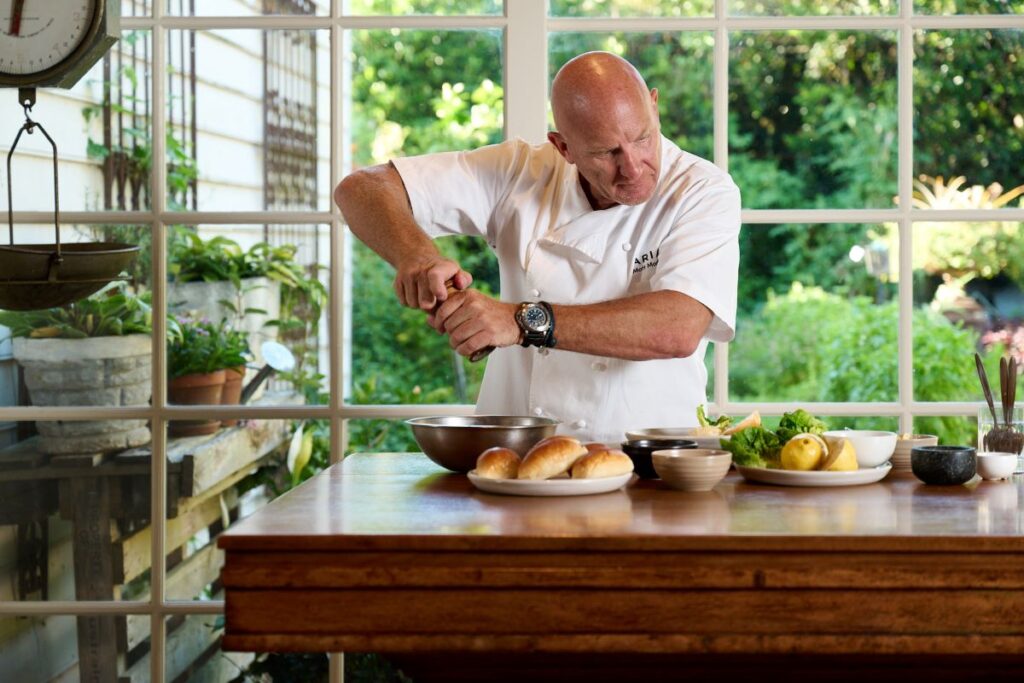 Chef Matt Moran adds seasoning to a metal bowl in preparation for the A Table Somewhere festival, one of Australia's best food and drink festivals - Luxury Escapes