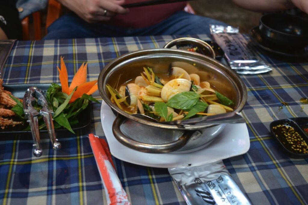 A bowl of Vietnamese seafood soup sits on a table at Vinh Khanh (Seafood Street), one of the stop-offs in the motorbike food tour through Ho Chi Minh City - Luxury Escapes