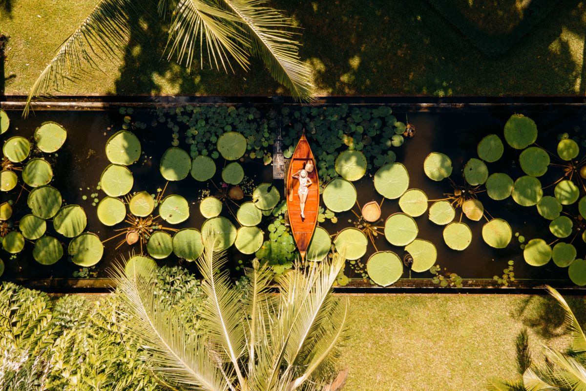 Aerial view of a woman lying on woman boat in a lily pond – Luxury Escapes, Anantara Bophut Koh Samui Resort.