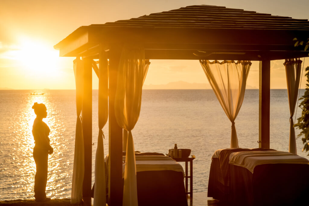 Two massage tables under a beach cabana at sunset with a masseuse standing nearby – Luxury Escapes, InterContinental Koh Samui Resort.