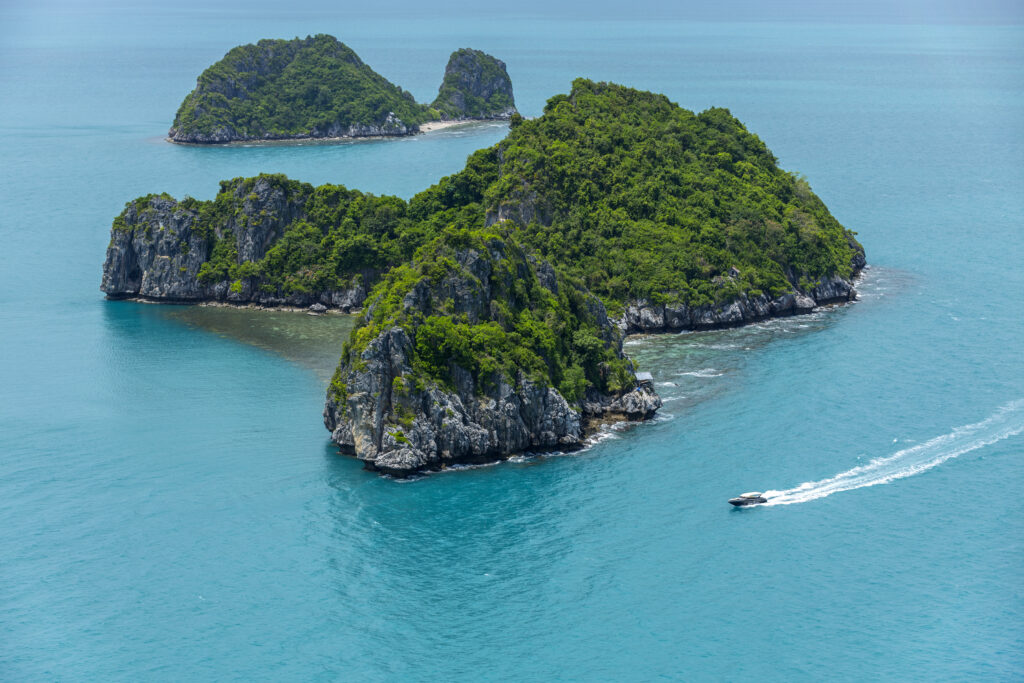 A speedboat moving past tropical archipelago islands in a turquoise sea – Luxury Escapes, InterContinental Koh Samui Resort.