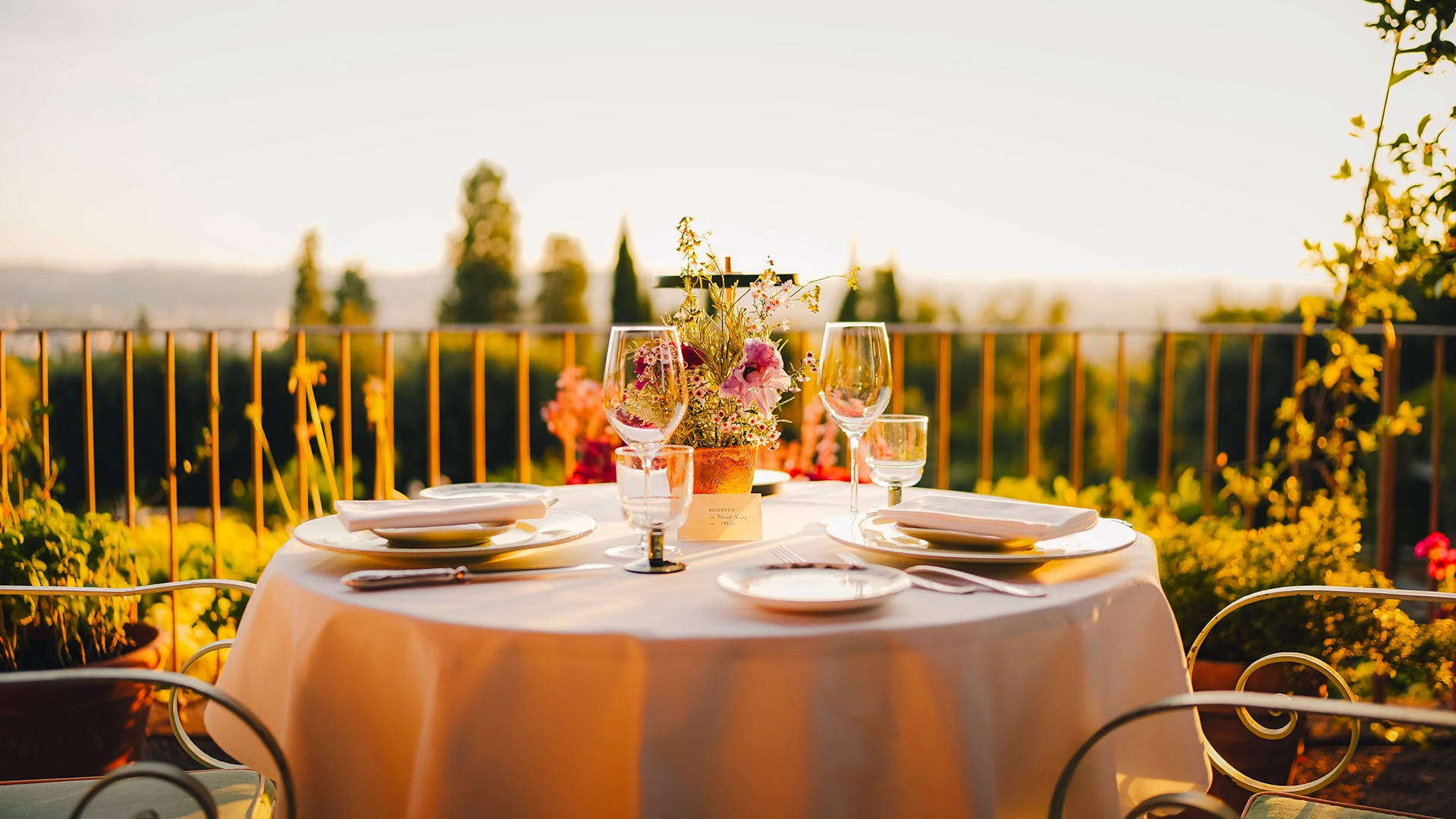 A table at an outdoor restaurant in Tuscany, spread with a white linen table, wine glasses and cutlery - Luxury Escapes