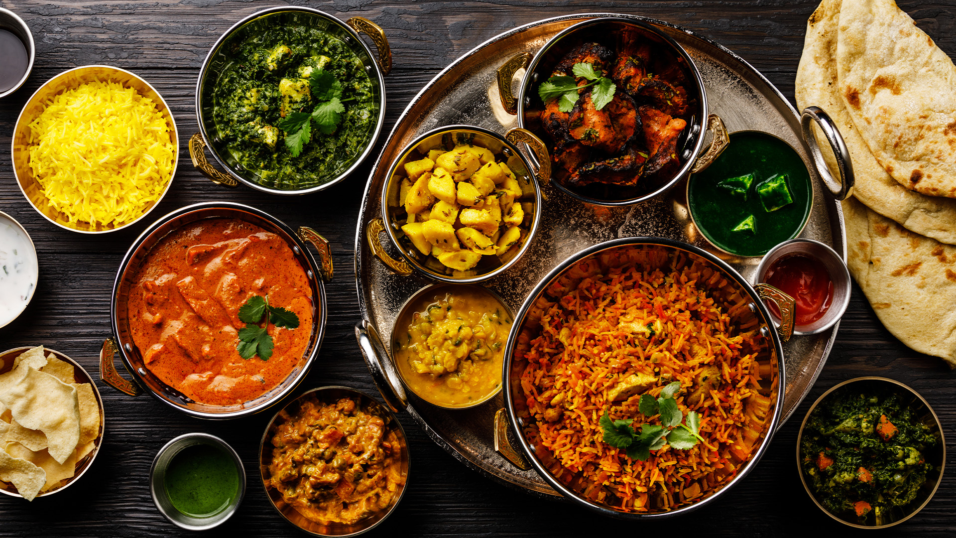 A delicious spread of North Indian delicacies like butter chicken, palak paneer, jeera alu, specially found in India's Golden Triangle – Luxury Escapes