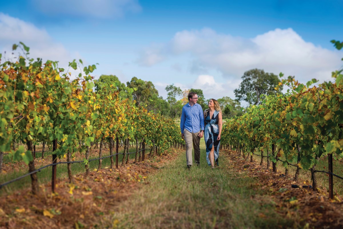 A couple walking through a vineyard near Oakes Cyprus Lakes Resort, which is one of the best places to spend a long weekend in Australia - Luxury Escapes
