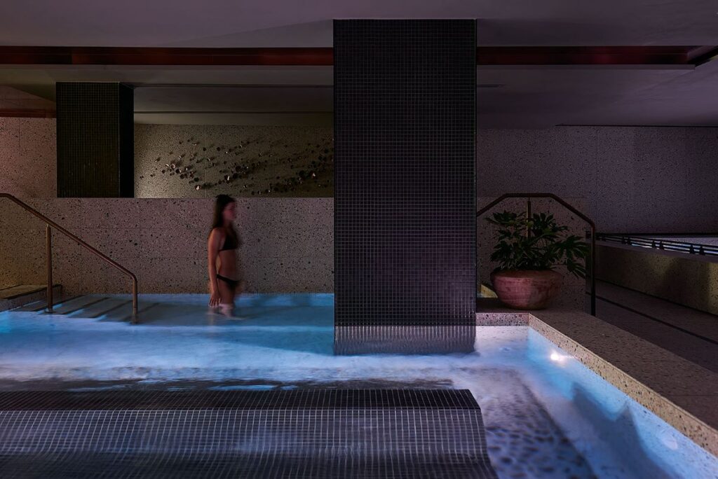 A guest steps into the warm pool at Aurora Spa & Bathhouse, one of the best things to do while staying at InterContinental Sorrento Mornington Peninsula - Luxury Escapes
