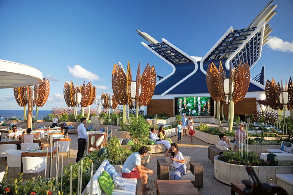 An array of people drink cocktails on the rooftop garden of the Celebrity Edge, one of Celebrity Cruises newest ships to sail New Zealand - Luxury Escapes