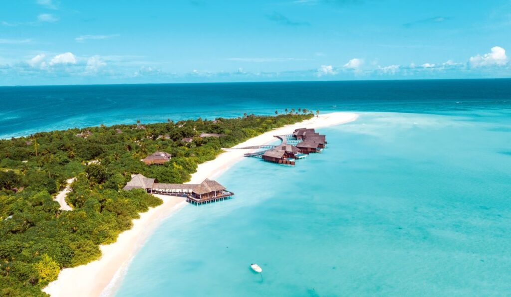 An aerial shot of Hideaway Beach Resort & Spa and the blue coastline, one of the best resorts to travel solo in the Maldives - Luxury Escapes