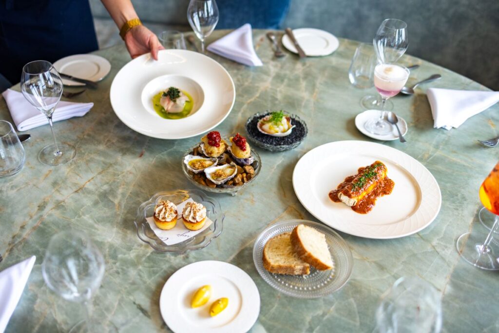 An array of dishes on white plates on a blue marble table at Audrey's, one of InterContinental Sorrento Mornington Peninsula's many dining options - Luxury Escapes
