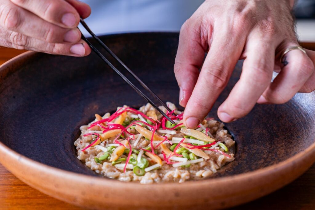 A close up of a chef arranging a rice dish with chop sticks at one of Phuket's best restaurants, PRU - Luxury Escapes