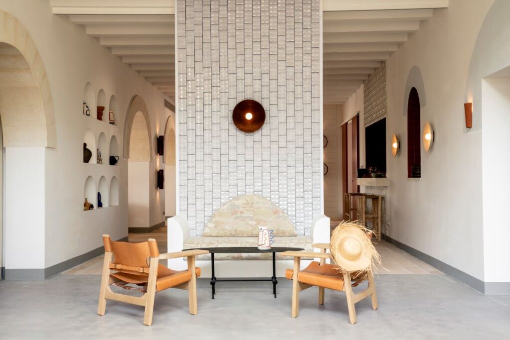 Two rattan chairs and a white tiled pillar stand in the lobby area of Menorca Experimental, one of the most luxurious stays in Spain - Luxury Escapes