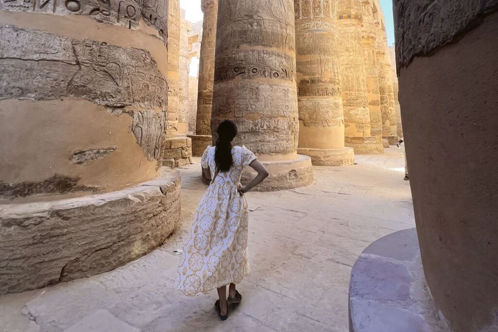A woman in a white dress stands in the Karnak Temple, one of the best experiences in Egypt - Luxury Escapes