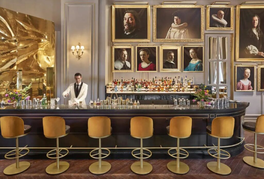 A bartender pouring a drink in front of a series of gold frames, at Mandarin Oriental Ritz, Madrid, one of the most luxurious hotels in Spain - Luxury Escapes