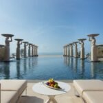 The iconic statues lining the infinity pool at The Mulia, one of the most iconic hotels and resorts in the world - Luxury Escapes