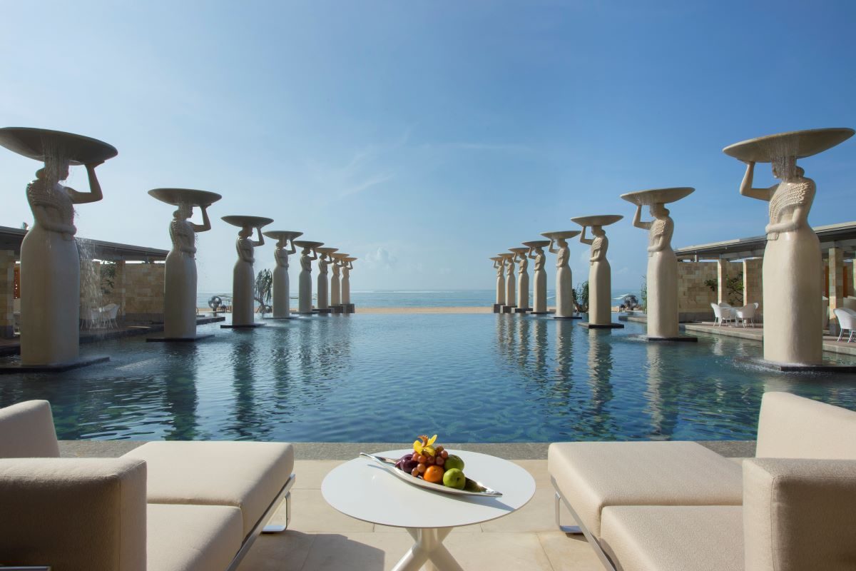 The iconic statues lining the infinity pool at The Mulia, one of the most iconic hotels and resorts in the world - Luxury Escapes