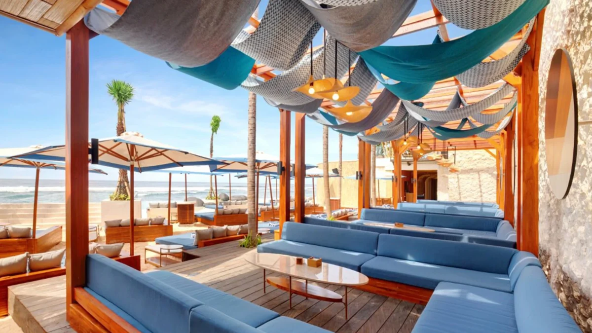 Beach cabanas at Tropical Temptations Beach Club, decorated with blue cushions on banquets, blue and white streamers and bamboo accents.