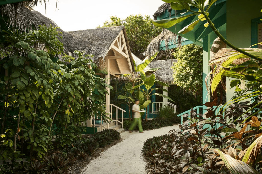 A team member walking out of Fehi Spa and into Seaside Finolhu Baa Atoll's lush gardens, one of the Maldives most unique resorts - Luxury Escapes