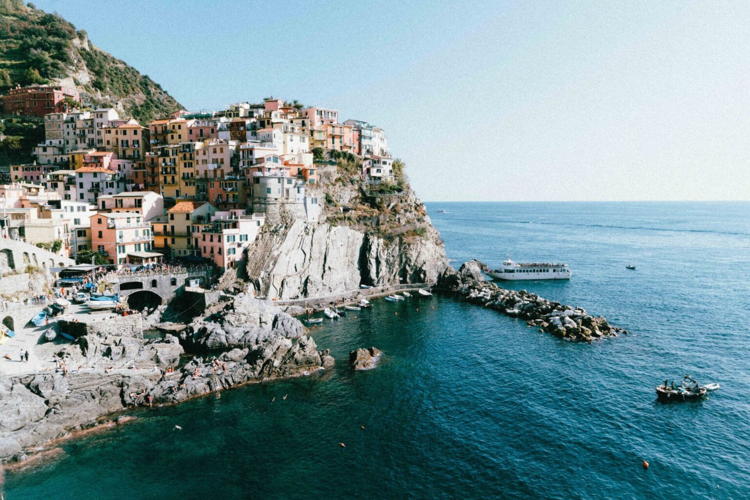 The sun-drenched cliffs and pastel-coloured houses of Manarola in the Cinque Terre, one of Europe's most popular summer destinations.