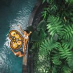 Travel happy couple in love eating floating breakfast in jungle swimming pool. Awakening in morning. Black rattan tray in heart shape, Valentines day or honeymoon surprise, view from above - Dream by Luxury Escapes