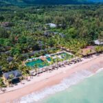 The palm-fringed beachfront infinity pool at Beyond Resort Khaolak, one of Thailand's best hotels. - Luxury Escapes