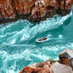 A small vessel navigates the narrow passage of the Horizontal Falls in Western Australia's Kimberley region, one of the ultimate activities to add to your Australia bucket list - Luxury Escapes