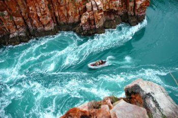 A small vessel navigates the narrow passage of the Horizontal Falls in Western Australia's Kimberley region, one of the ultimate activities to add to your Australia bucket list - Luxury Escapes