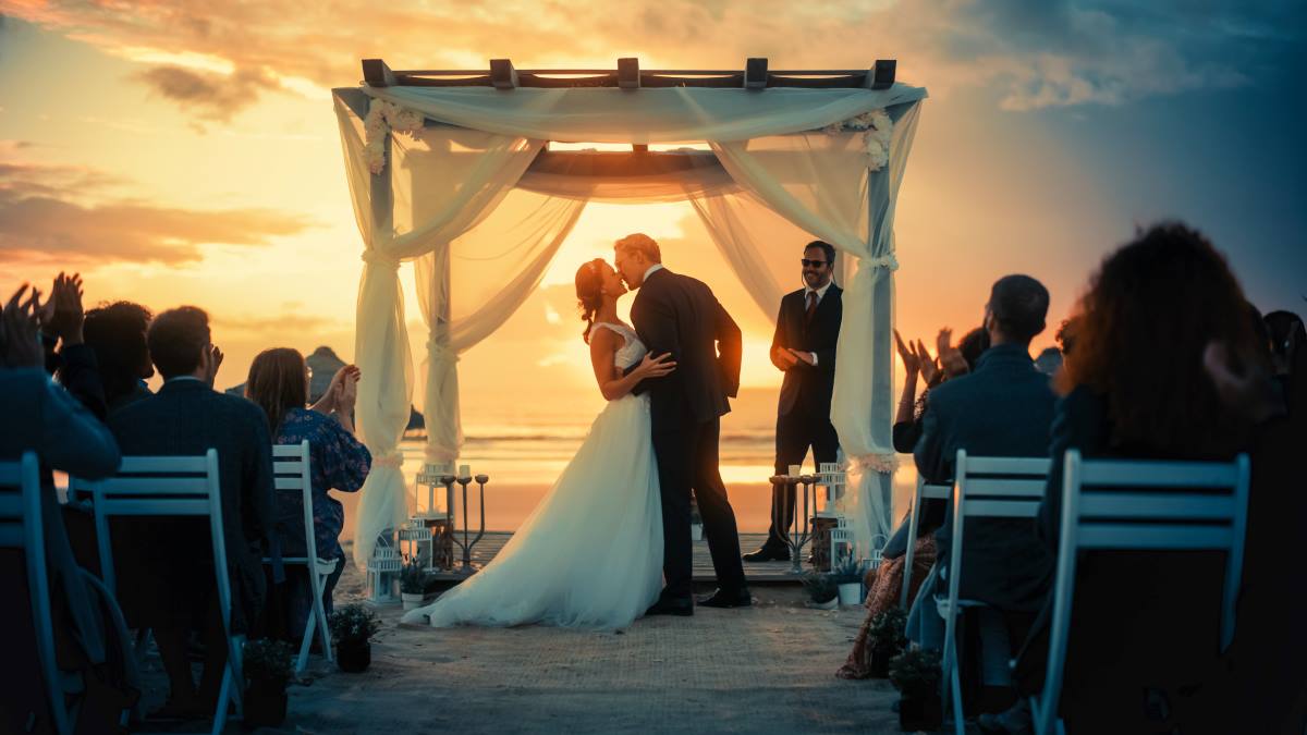 A happy couple celebrates their wedding on a beautiful beach - Luxury Escapes