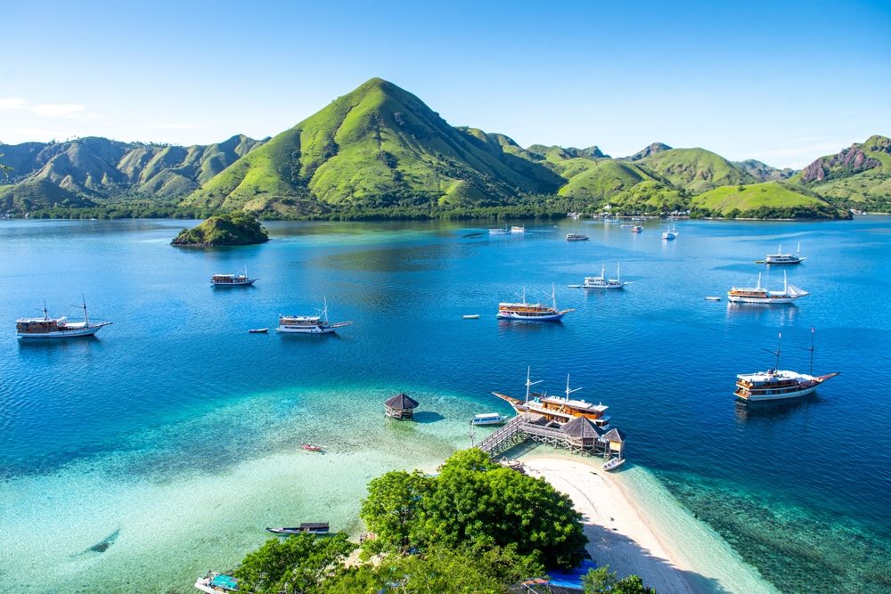 View of Kelor Island within Komodo National Park with Phinisi Boats in the water - Luxury Escapes