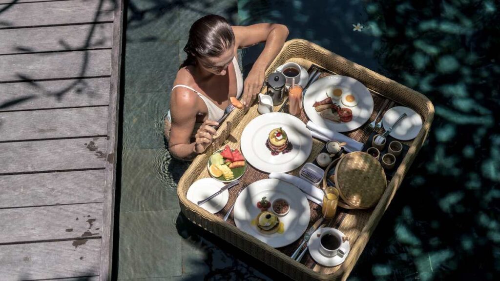 Woman enjoying a floating breakfast in the pool at Kayumanis Nusa Dua - Luxury Escapes