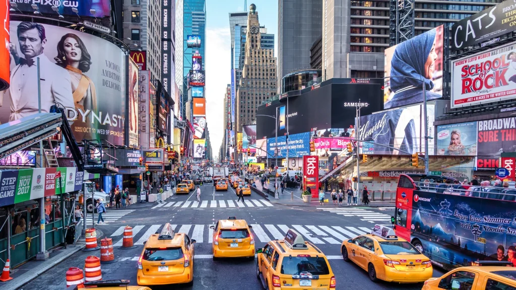 A busy shot of bustling Times Square, while a group of bright yellow taxis cross the intersection - Luxury Escapes